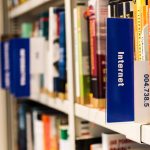Estante de biblioteca com livros sobre internet e tecnologia, representando a relação entre leitura e cultura digital.