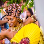 Dançarina afro-brasileira usa traje colorido e joias durante uma celebração cultural.
