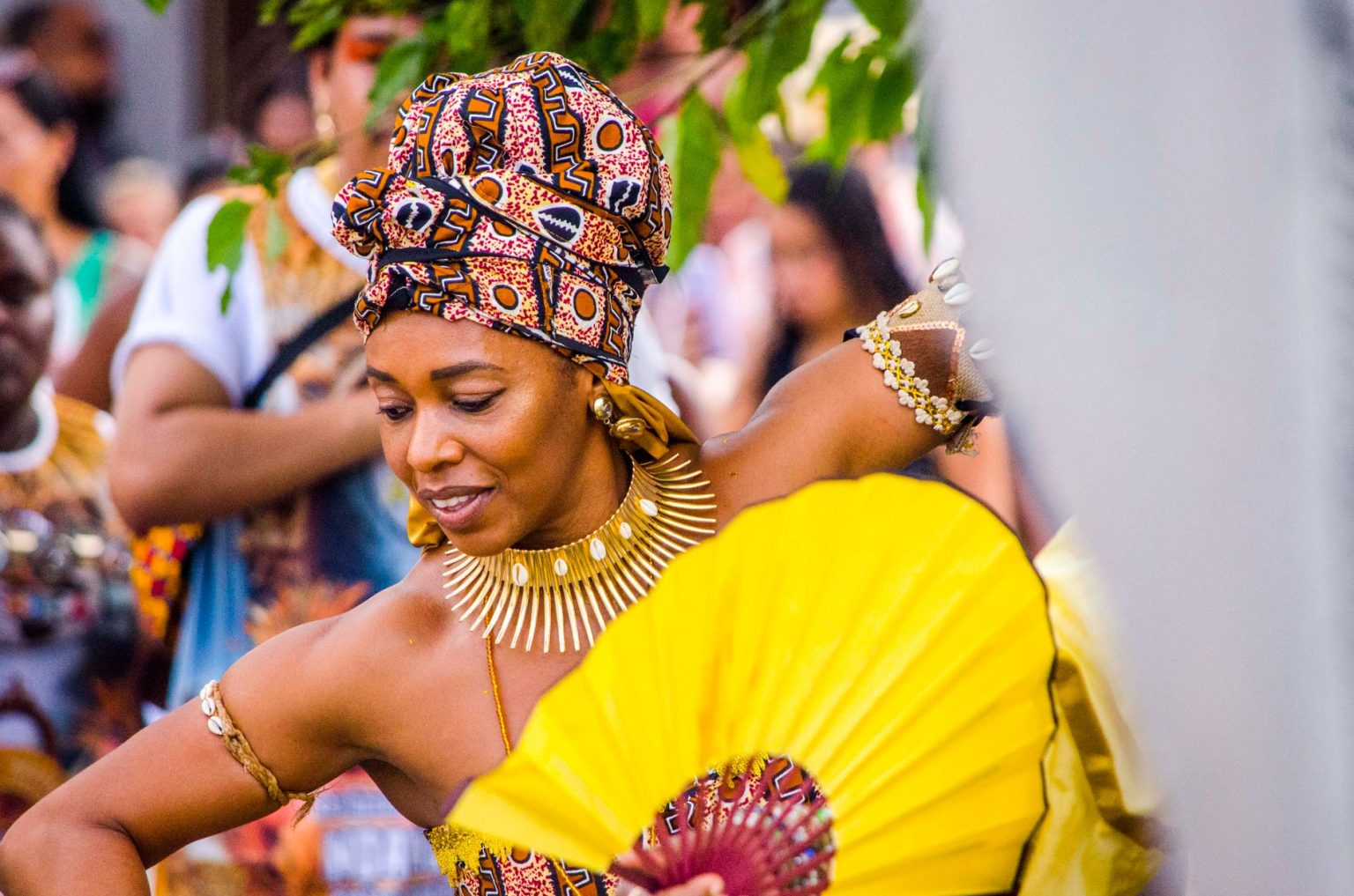 Dançarina afro-brasileira usa traje colorido e joias durante uma celebração cultural.