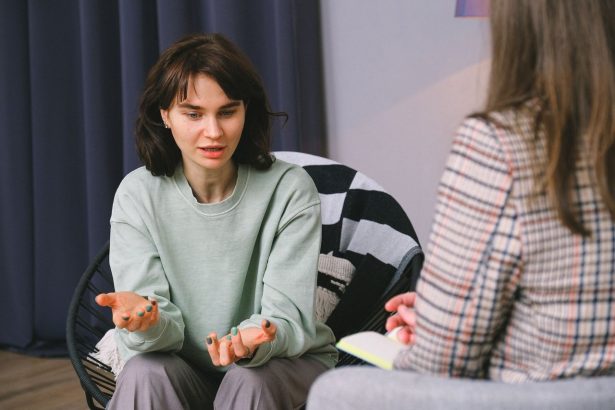 Mulher participa de uma entrevista em uma sala iluminada, diante de outra mulher que a escuta atentamente.