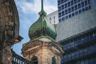 Conjunto arquitetônico em São Paulo que combina uma construção histórica ornamentada com estruturas modernas ao fundo.