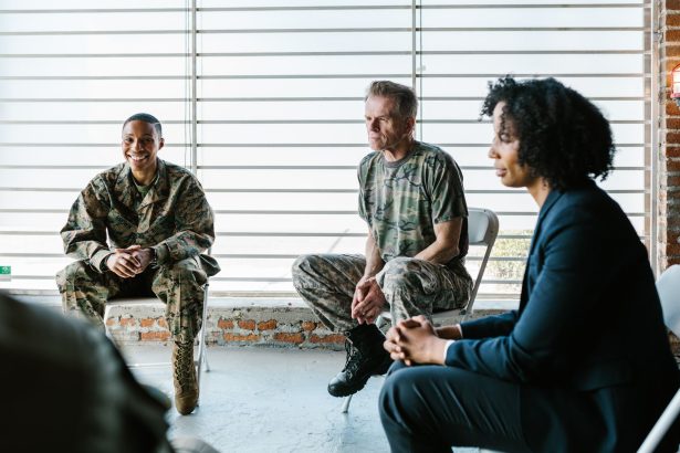 Grupo de militares veteranos participa de uma sessão coletiva de apoio psicológico com um profissional de saúde mental.